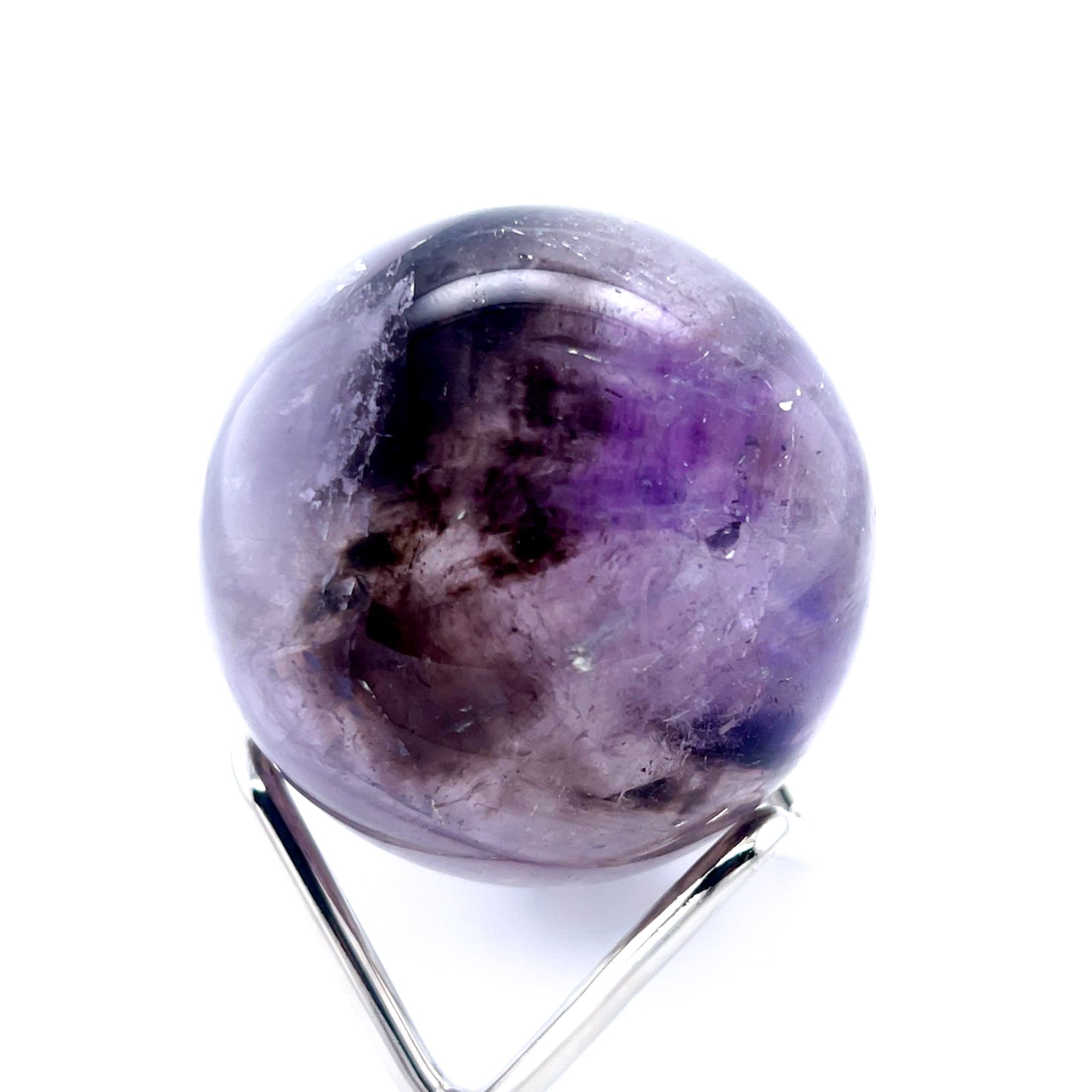 A polished purple amethyst crystal sphere displayed on a silver metal stand against a plain white background.
