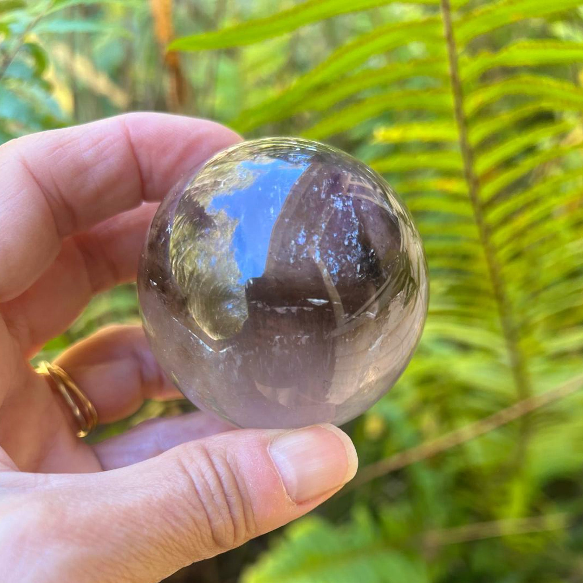 Hand holding Phantom Amethyst sphere showing scale in natural light