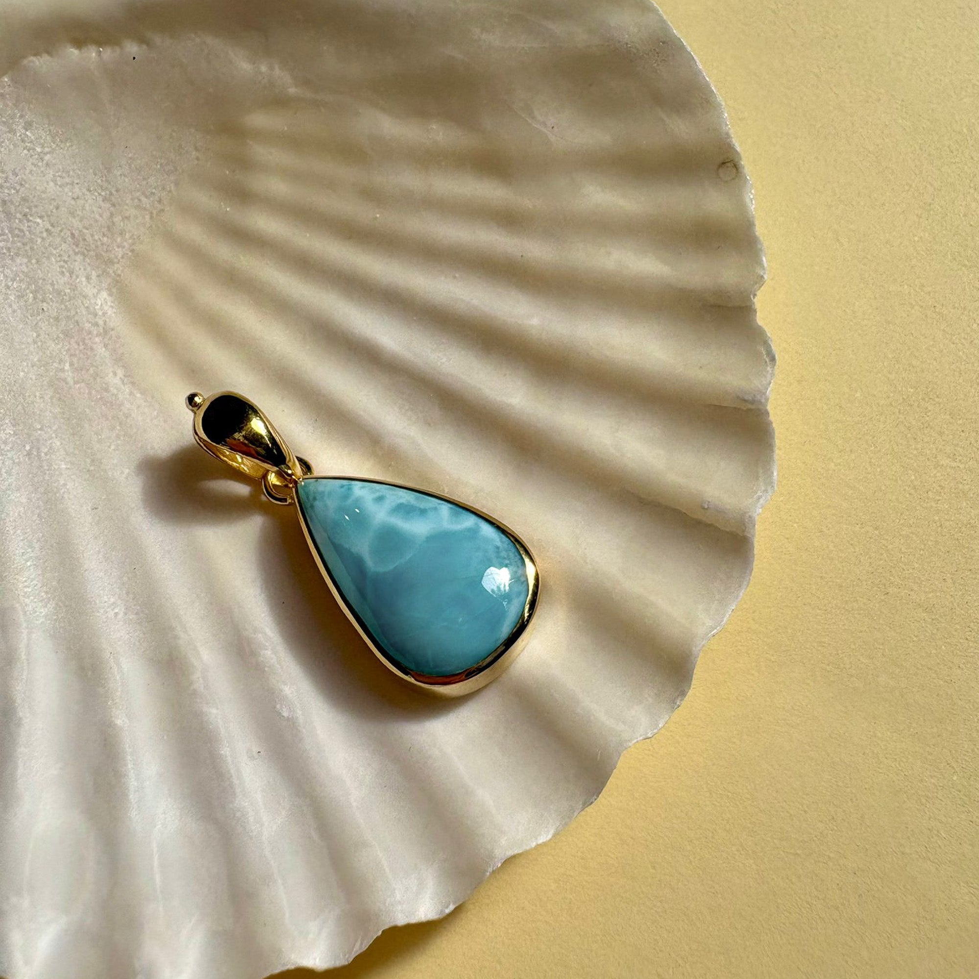 Larimar gold pendant styled on shell background