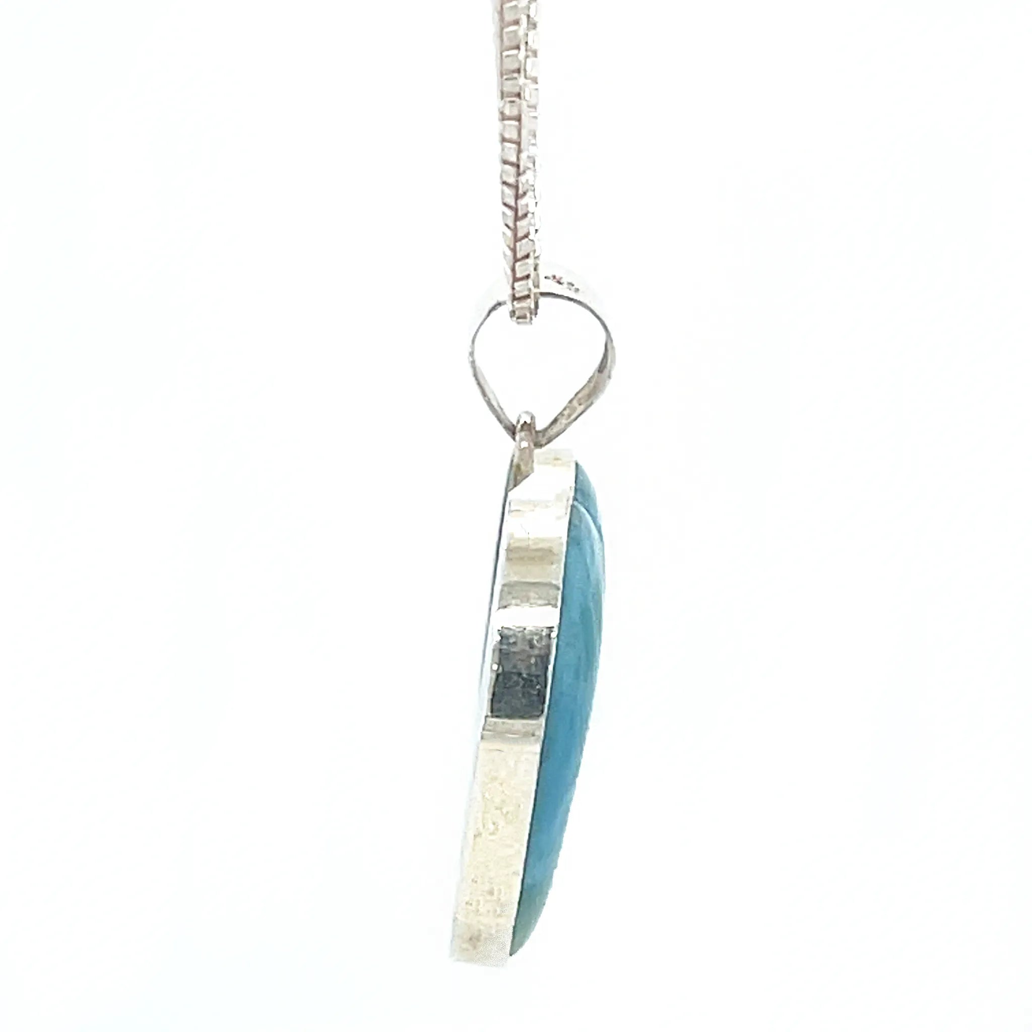 Side view of Larimar silver heart pendant showing polished gemstone setting